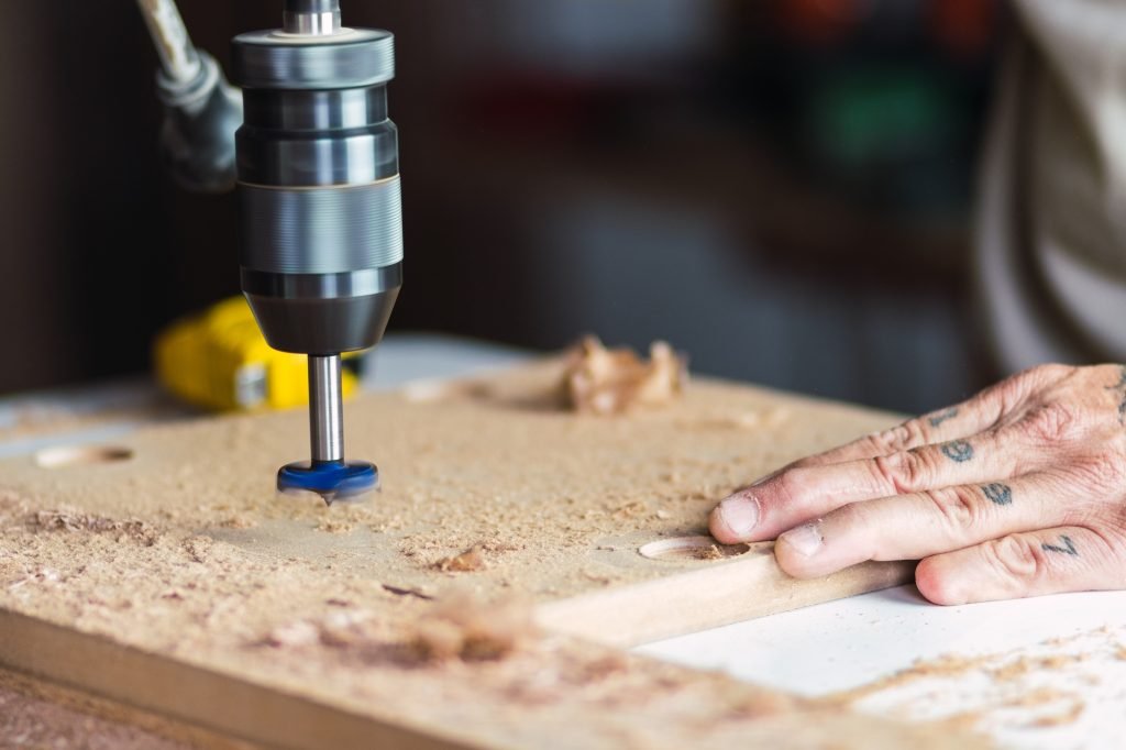 Woodworker using drilling machine in joinery